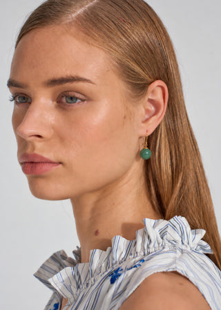 Model wearing MEGAN PARK Green Onyx Drop Earrings featuring polished green gemstone spheres on fine gold hooks.